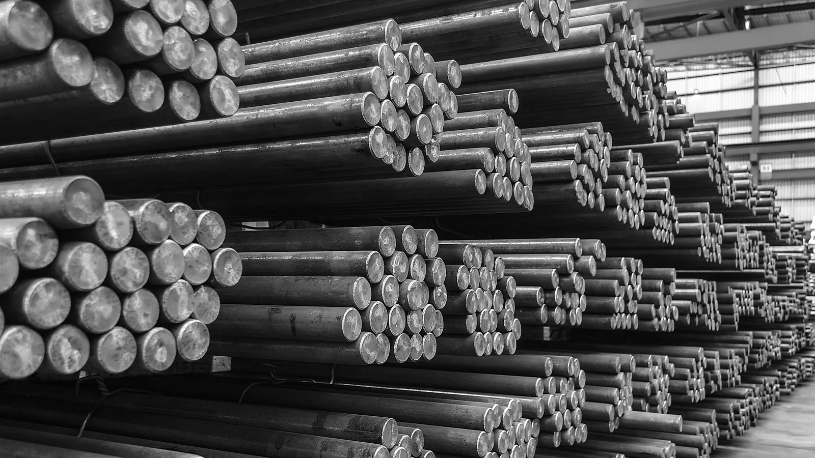 Rows of solid round steel bar bundles stored on industrial warehouse racks